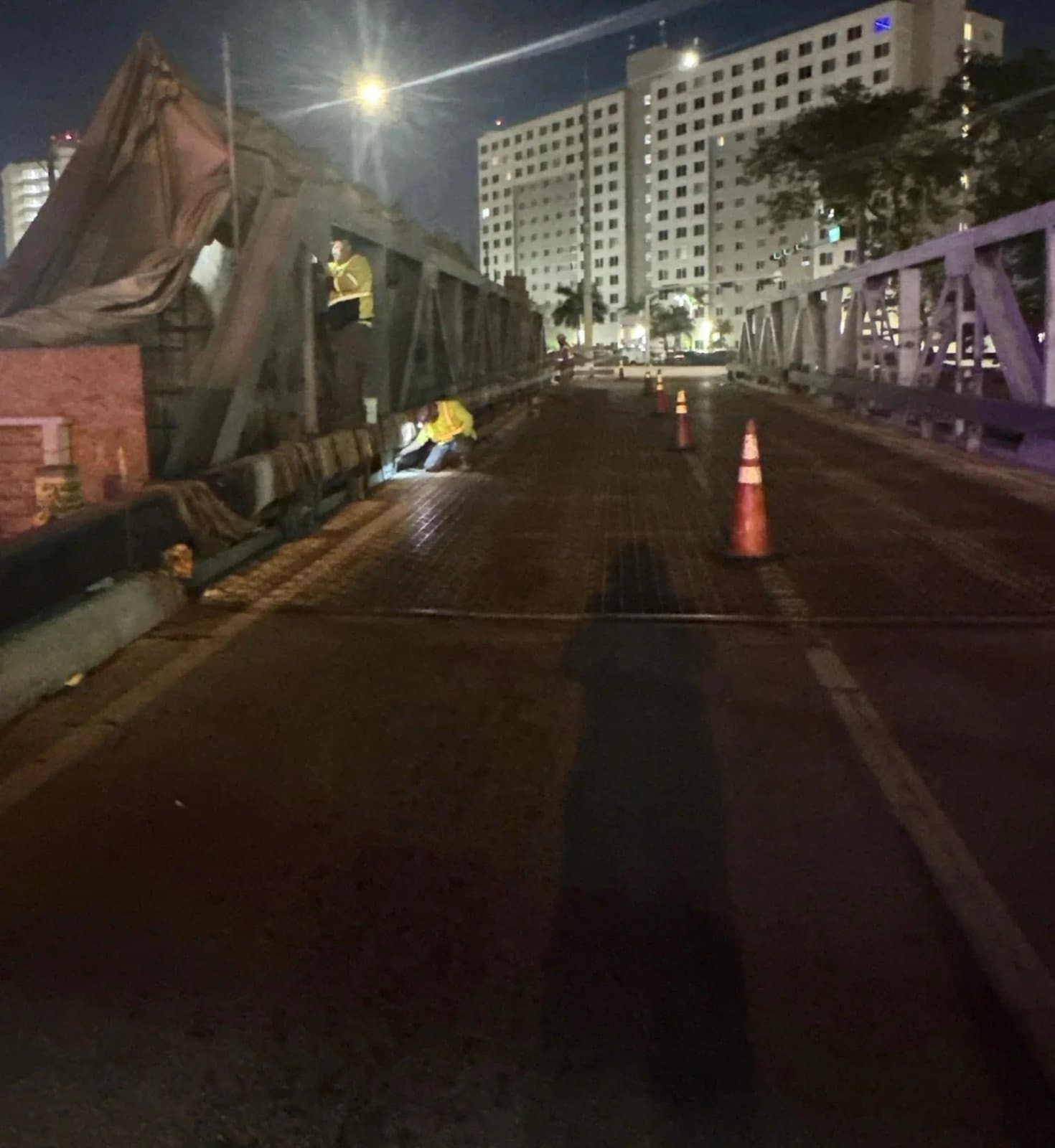 Crew member on the bridge deck at night with traffic cones set for a lane closure