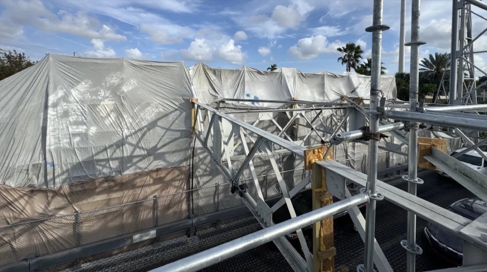 Containment tarps wrapped over the truss scaffold in daylight